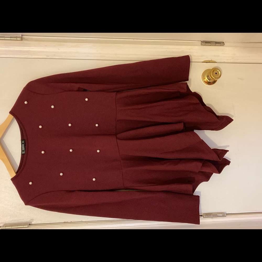 Burgundy top with long sleeves and white pearls.
